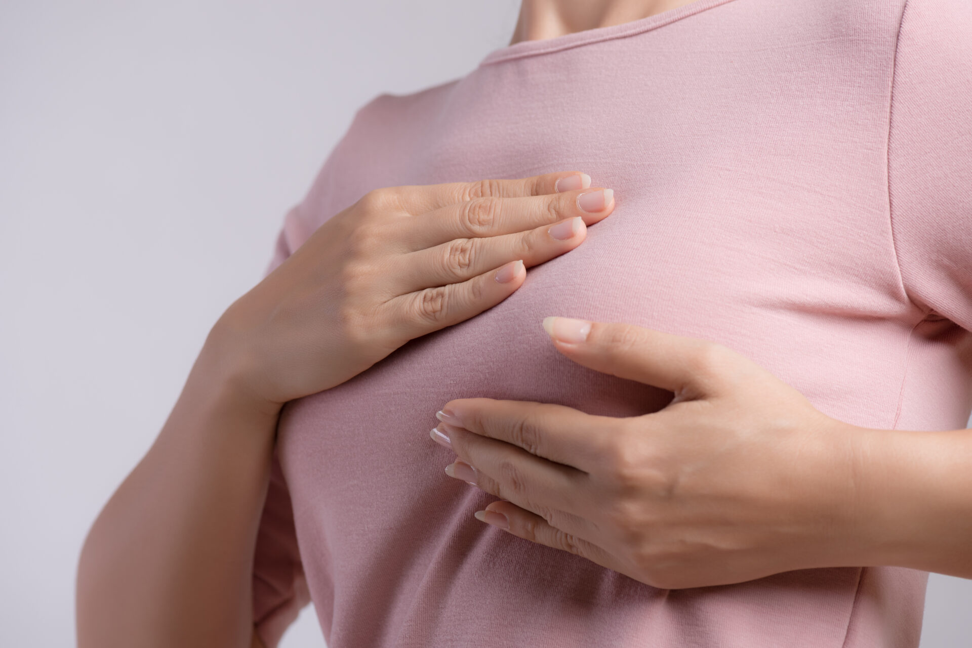Woman hand checking lumps on her breast for signs of breast canc
