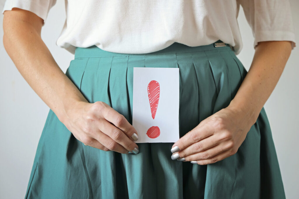 Woman healthcare and gynecology concept. A woman's hands holding an exclamation mark on belly or stomach